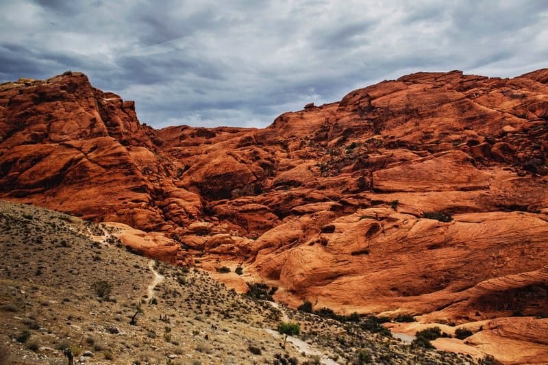 Red rock formations under a cloudy sky in a desert landscape.