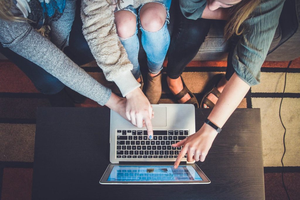Three people around a laptop, pointing and collaborating.