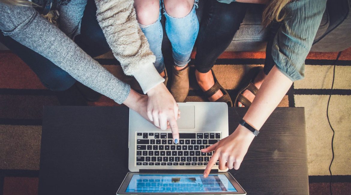 Three people around a laptop, pointing and collaborating.