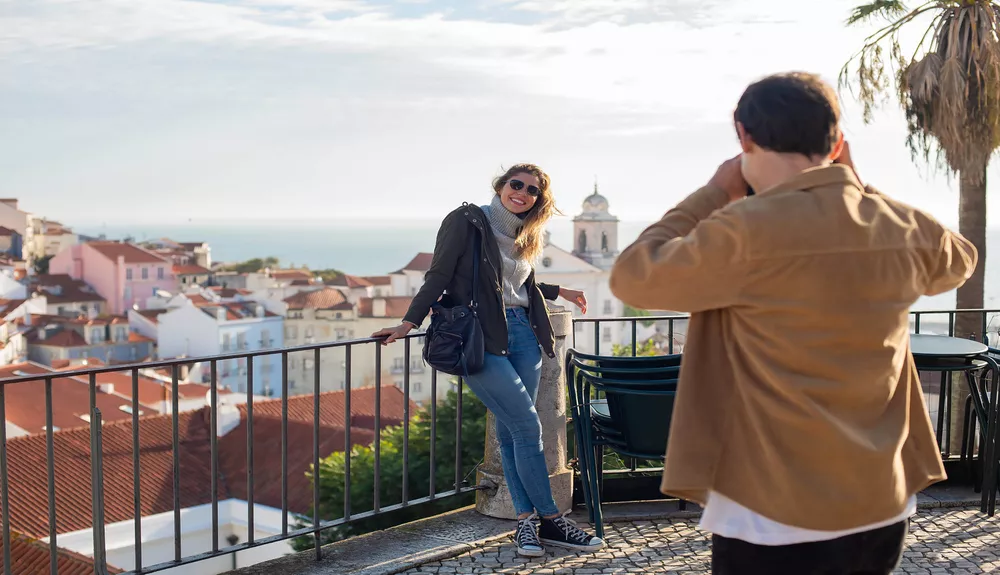 Two people enjoying a scenic city view from a balcony with a clear sky in the background.
