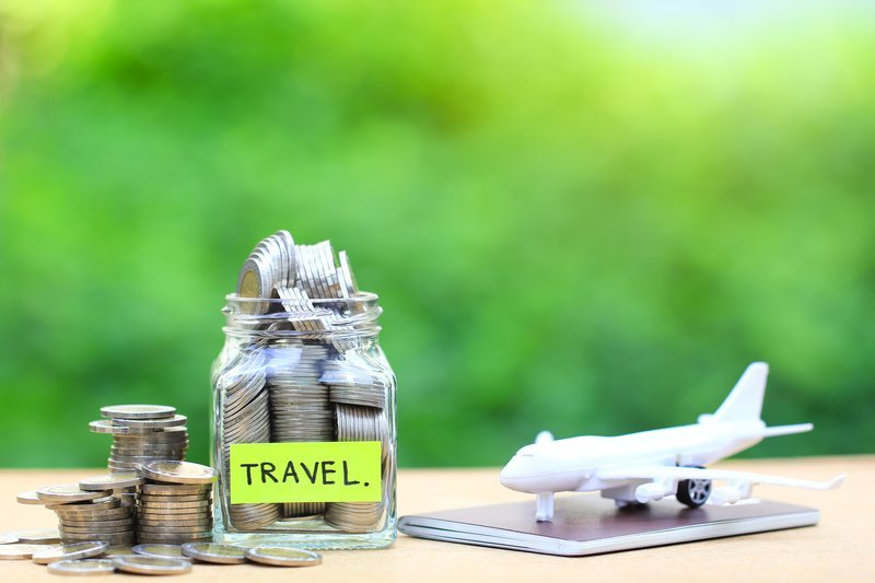 AAMP Agency - Changes Every Tourism Business Needs to Make to Adapt to Travel Restrictions 1 Jar of coins labeled "TRAVEL" with a toy airplane beside it, symbolizing travel savings.