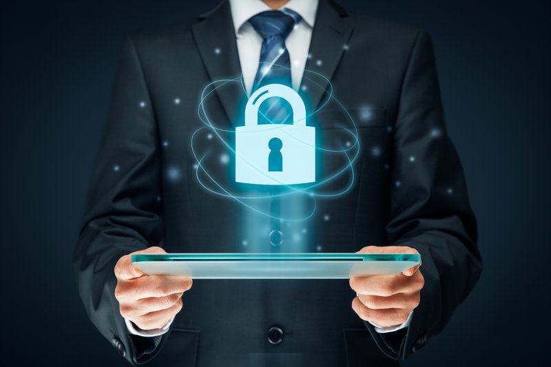 Businessman holding a tablet projecting a holographic padlock, symbolizing digital security.