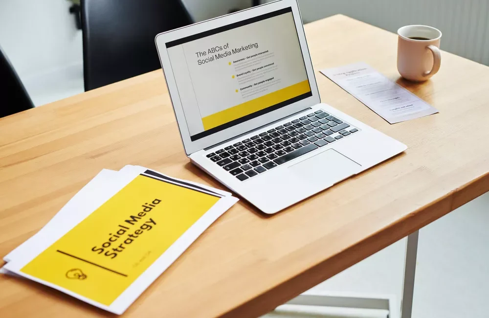 Laptop on a desk displaying "Social Media Marketing" presentation next to coffee and strategy documents.