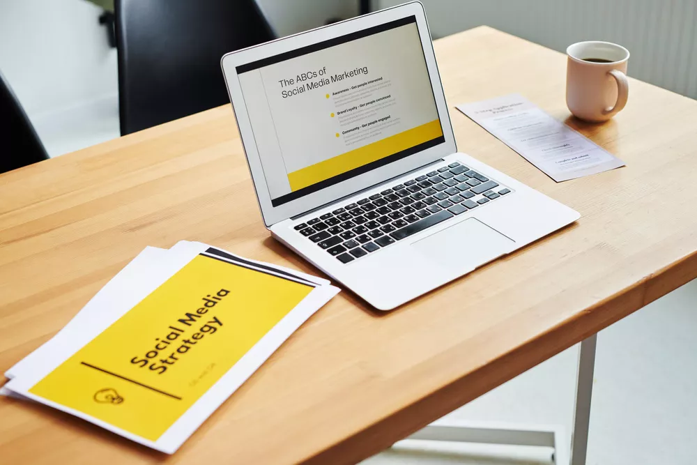 Laptop on a desk displaying "Social Media Marketing" presentation next to coffee and strategy documents.
