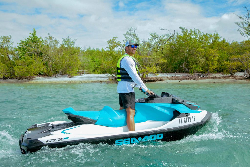A man speeds on a jet ski, creating splashes in the ocean. AAMP Agency.