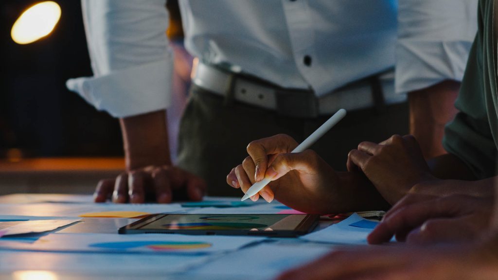 Professionals collaborating over graphs and charts on a table.