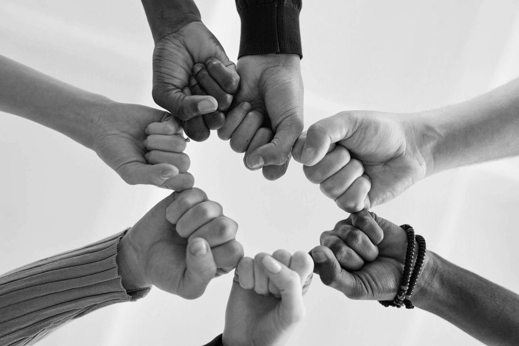 Diverse group of hands forming a circle, symbolizing unity and teamwork.