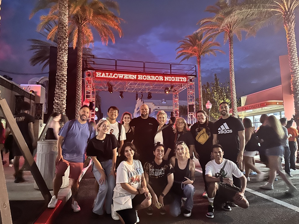 A group of people smiling and posing in front of palm trees, captured by AAMP Agency.